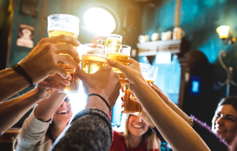 Group of happy friends drinking and toasting beer at brewery bar restaurant -