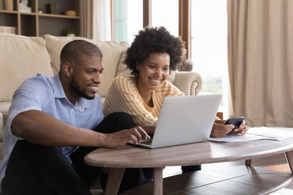 couple using laptop, looking at screen, smiling, laughing, getting good news.