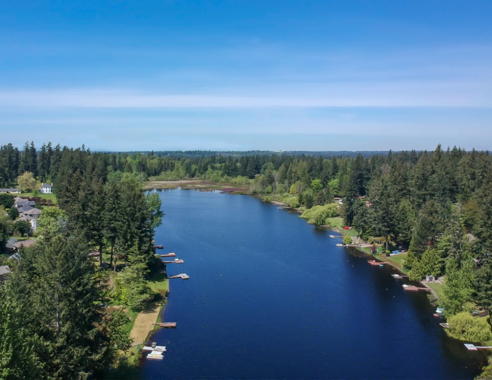 Lovely Lake Holm Water Access Site in springtime with the surrounding forest and homes and the sky and clouds in Auburn Washington.