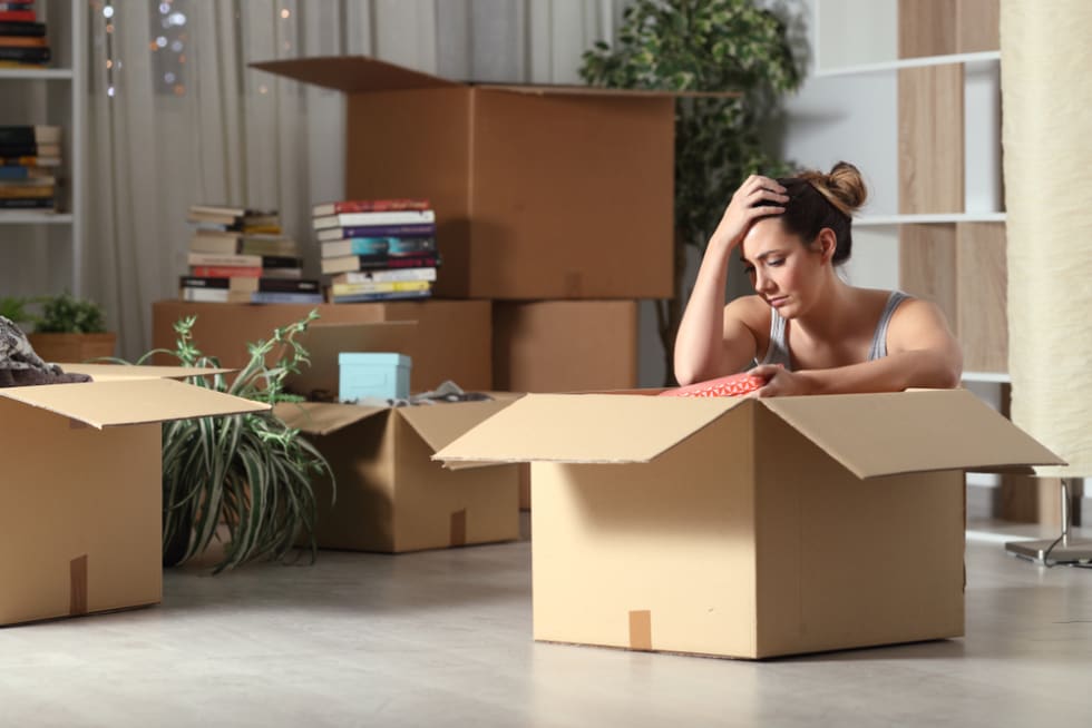 Sad evicted tenant moving home boxing belongings sitting on the floor in the night