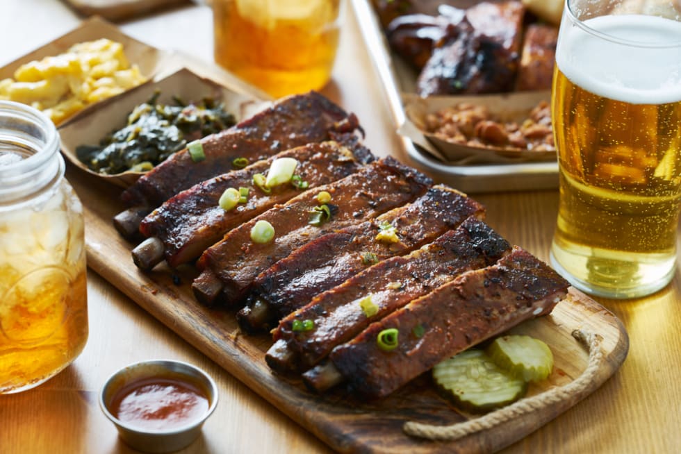 st louis style bbq ribs on table top with sweet tea, beer, collard greens and mac & cheese