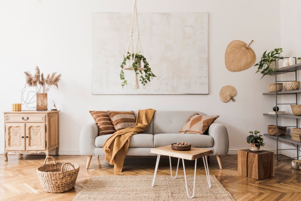 The stylish boho compostion at living room interior with design gray sofa, wooden coffee table, commode and elegant personal accessories.