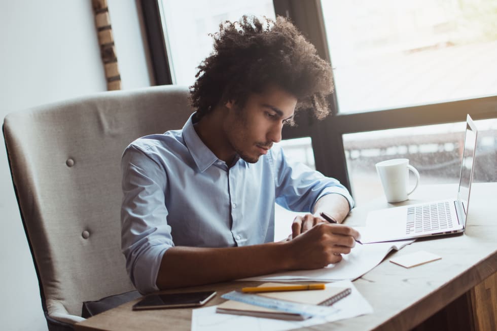 young businessman writing something while sitting at his office desk - apartment budget