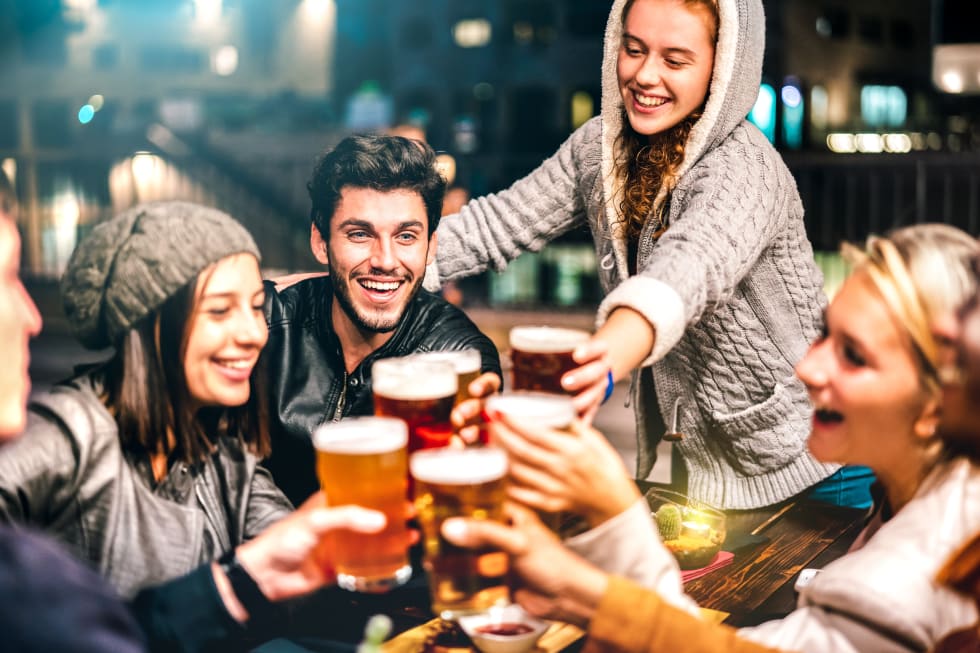 Happy people drinking beer at brewery bar out doors - Multicultural life style concept with genuine friends enjoying time together at open air restaurant patio