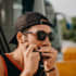 Barry D. Man in his thirties wearing dark glasses a cap and playing the harmonica.