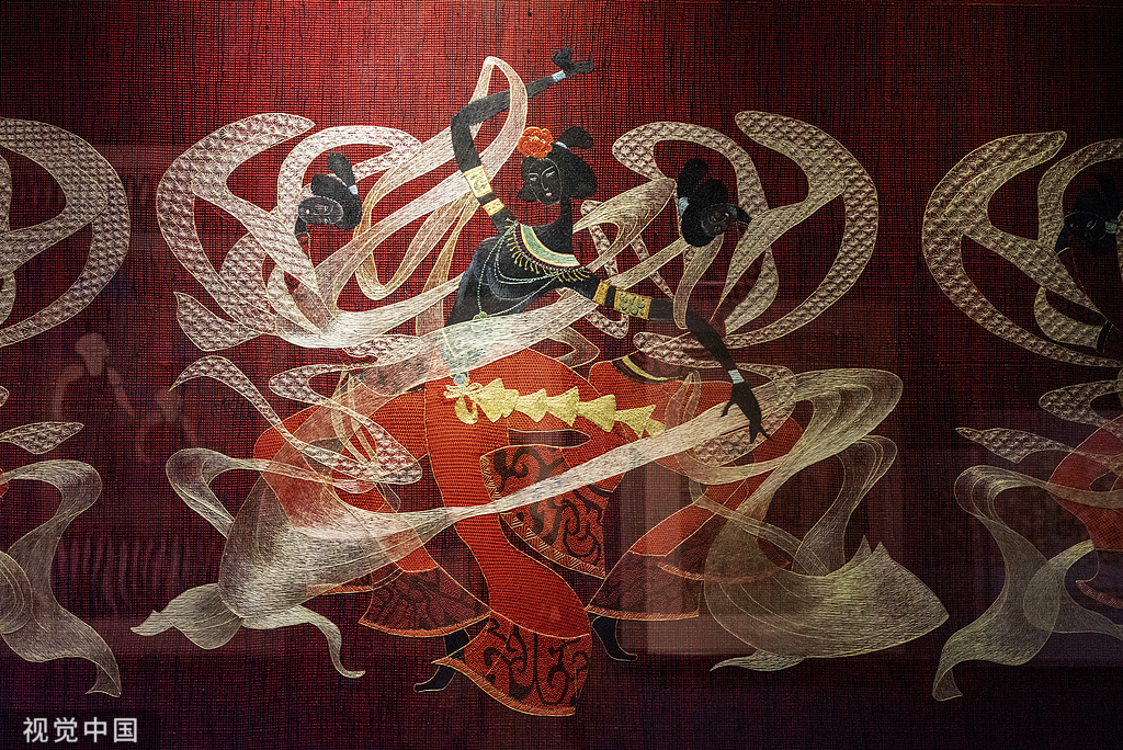 Flying figures embroidered on red fabric