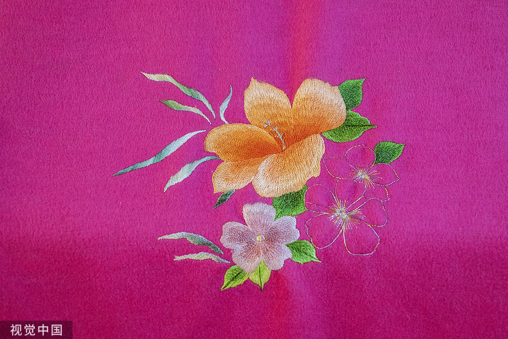 Orange flowers embroidered on magenta fabric
