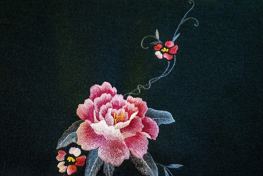 Pink peony embroidered on black fabric