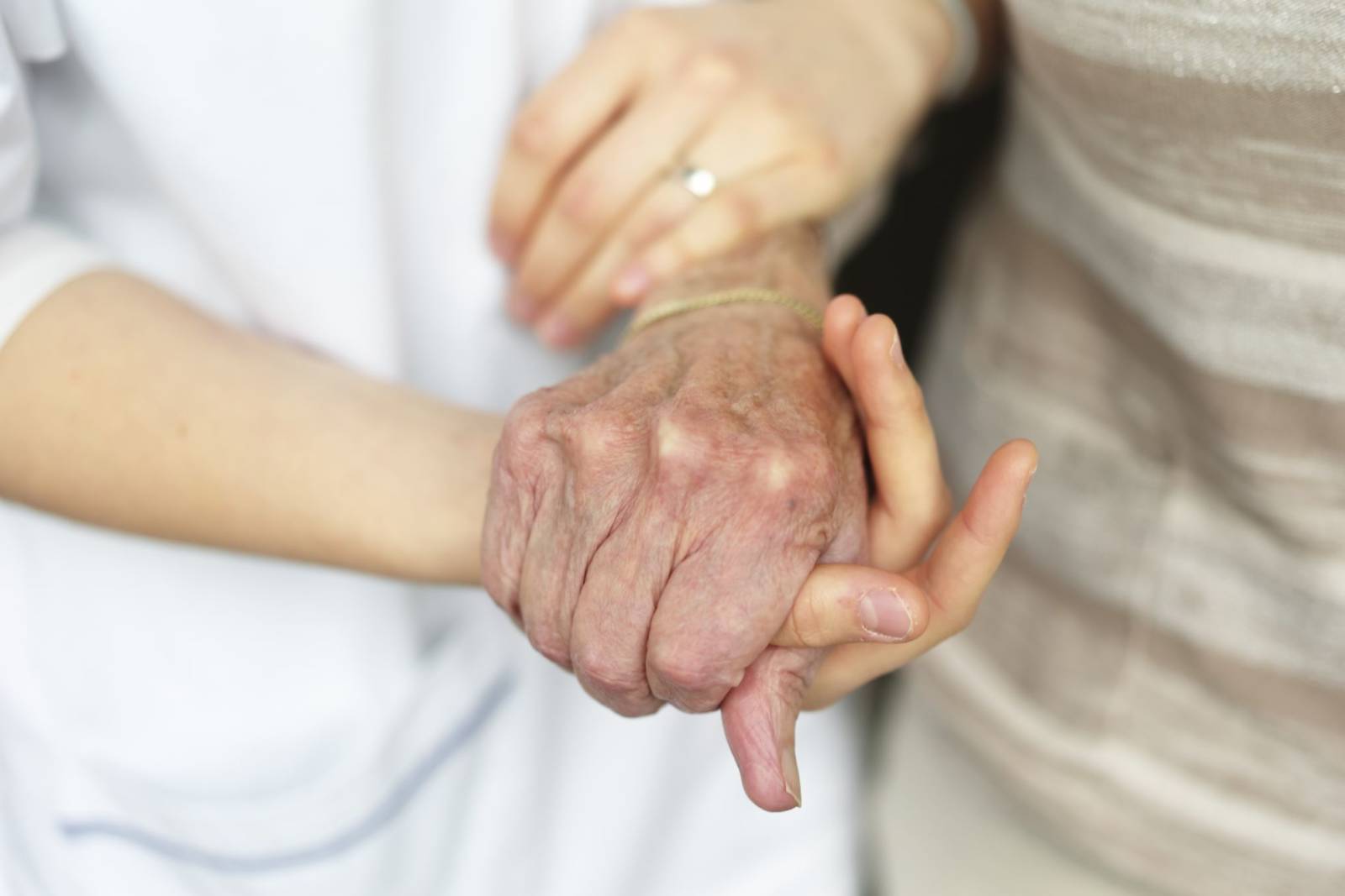 Sykepleier støtter en eldre person. Bilde kun av hendene deres