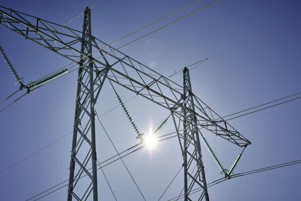 Strømmast mot himmel og sol
