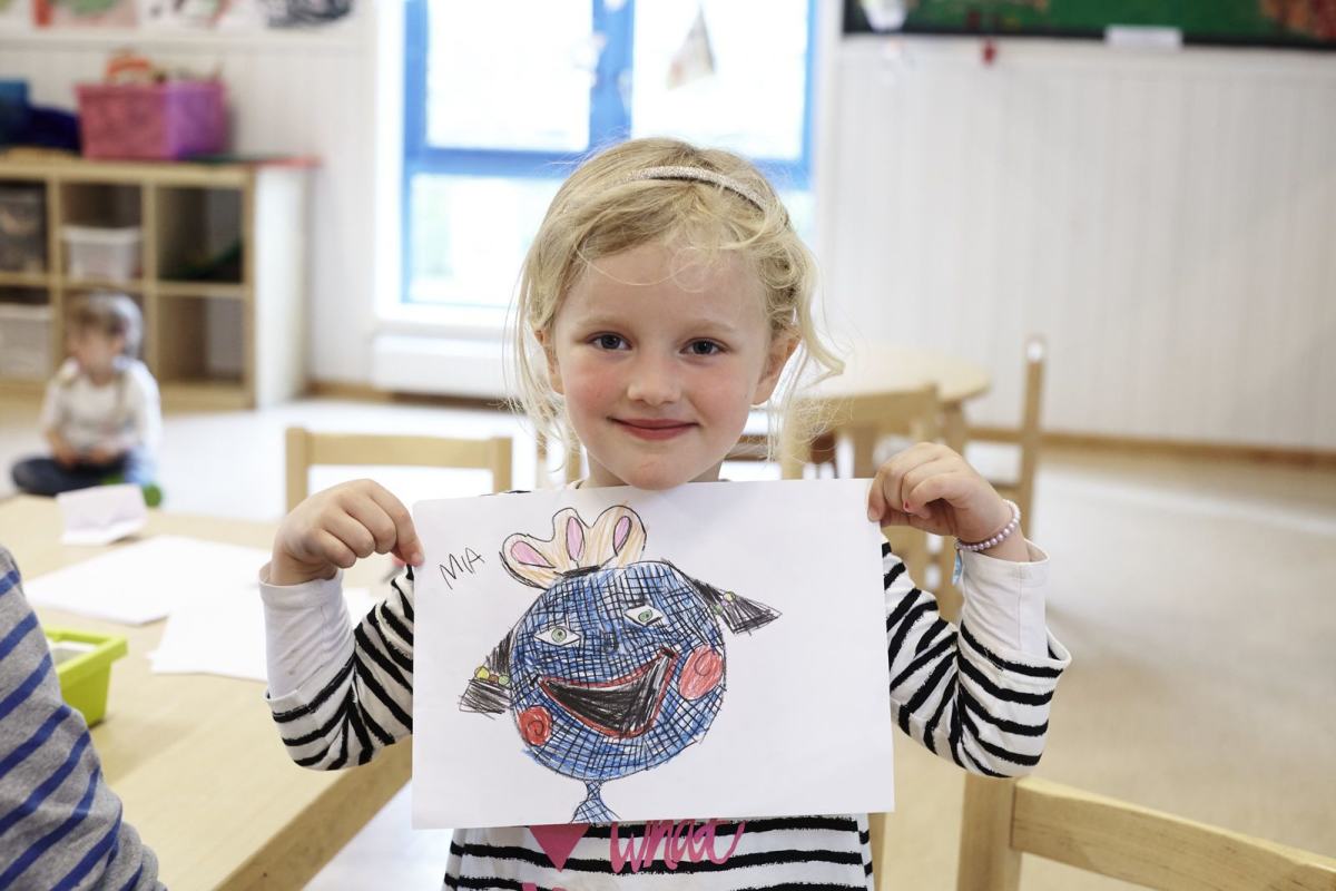 Et barnehagebarn viser stolt fram sin fargelagte tegning. Foto: Øivind Haug