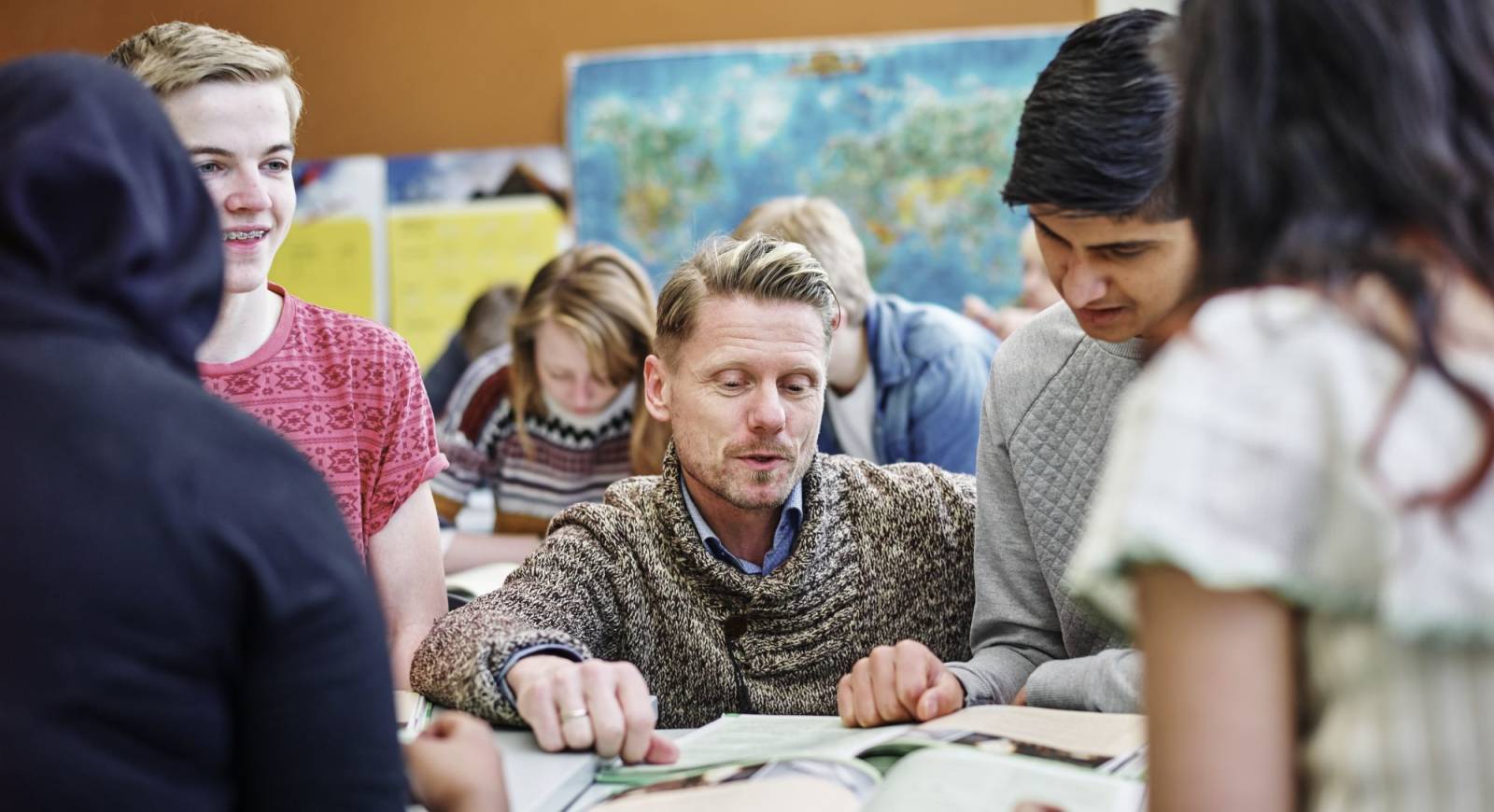 Lærer og elever som ser i bøker.