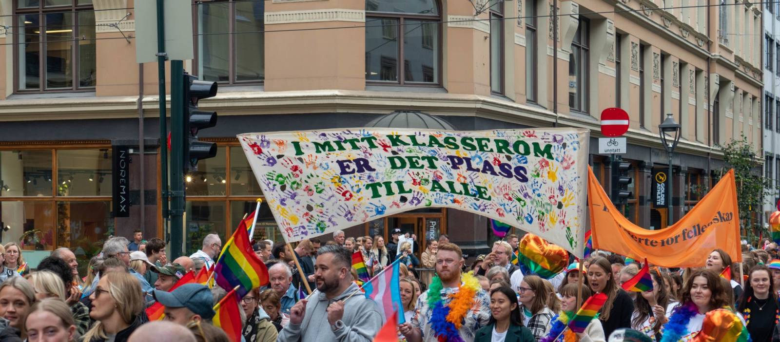 Mennesker i Pride-tog. Banner hvor det står "I mitt klasserom er det plass til alle"