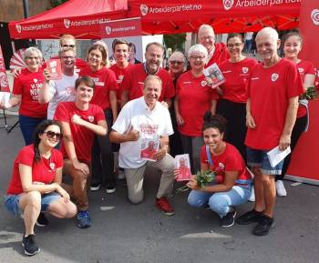 Gruppebilde av blid gjeng som står på stand