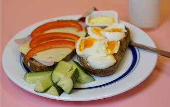 Tallerken med to brødskiver, agurk og et glass melk