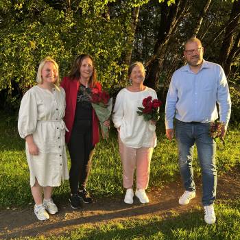 Åse Kristin, Anne Berit, Eva og Sindre smiler utendørs med roser