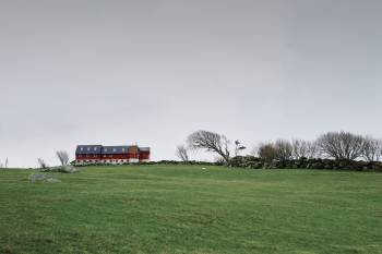 En enslig låve står i midten av et grønt gressfelt, et steingjerde strekker seg langs plenen. Foto: Øivind Haug