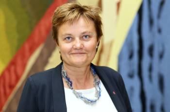 Kvinne som smiler til kamera. Fargerik bakgrunn.