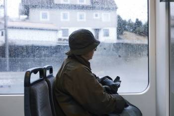 En eldre kvinnelig busspassasjer sitter og ser på regnet ut vinduet. Foto: Øivind Haug