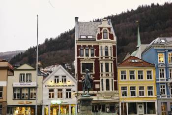 En rekke fargerike småhus på et torg i Bergen, i forgrunnen ser vi statuen av Ludvig Holberg. Foto: Øivind Haug