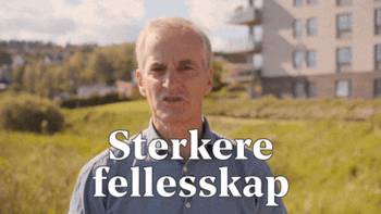Jonas Gahr Støre snakker utendørs med mye grønt gress og en lys boligblokk bak seg. Tekstet med: Sterkere fellesskap som gir trygghet og muligheter for alle.