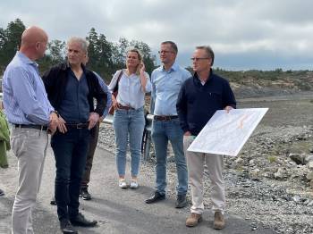 Jonas Gahr Støre lytter til Morrow og Arendal kommune på batterifabrikktomta i Arendal. 