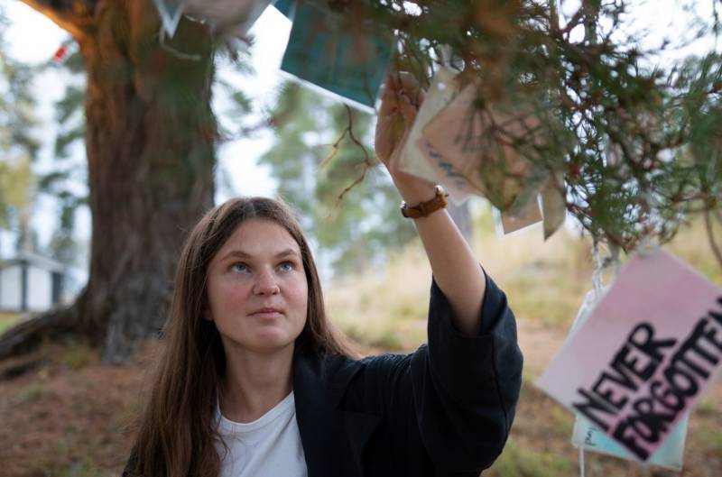 En jente leser på lappene som henger på verditreet på Utøya