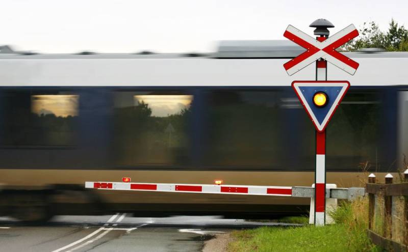 Tog som passerer en vei med bommen nede