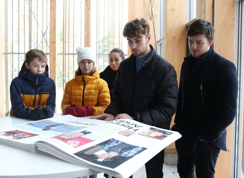 Fem barn og unge ser i en bok om 22. juli i Hegnhuset på utøya.