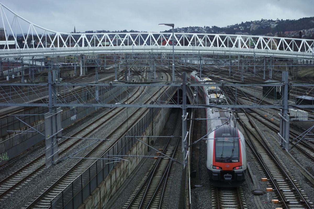 Et tog på vei inn til Oslo S kjører under broa som går på tvers av skinnene. Foto: Øivind Haug