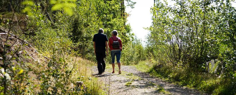 Et par som er ute å går på en grussti i skogen