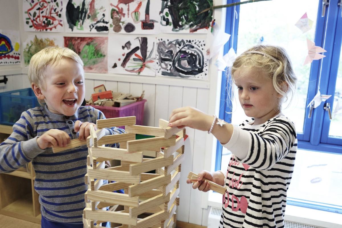 To barnehagebarn bygger et høyt tårn og stråler av glede. Foto: Øivind Haug