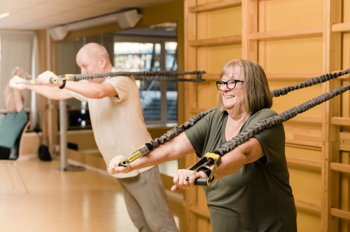 To eldre mennesker trener i gymsal