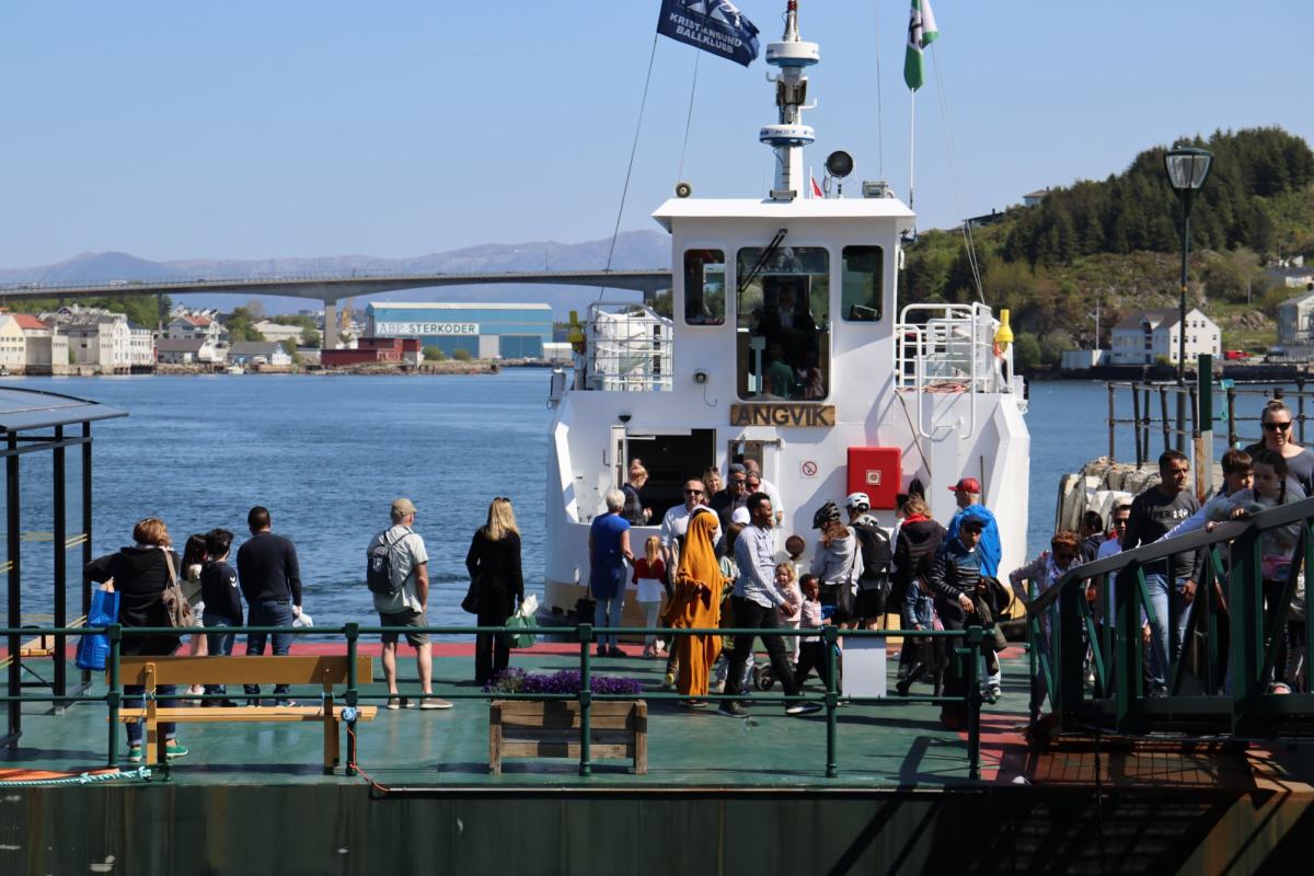 Bildet viser Sundbåten i Kristiansund komme til kai, mange passasjerer går ut av fergen på solskinnsdagen