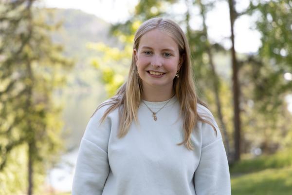 Sunniva står foran en bakgrunn av grønne trær