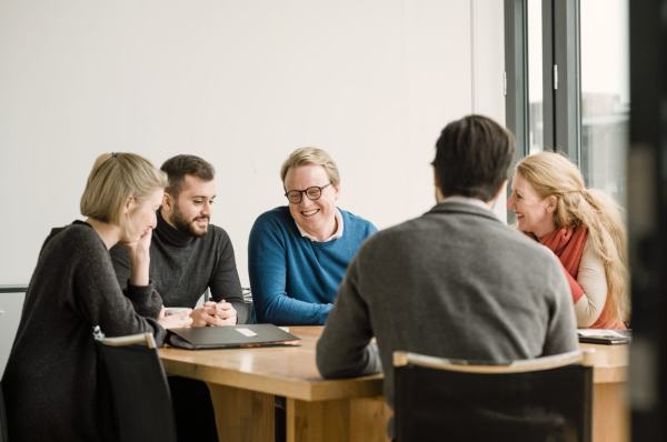 Mennesker på arbeidsplass, sitter rundt et bord.