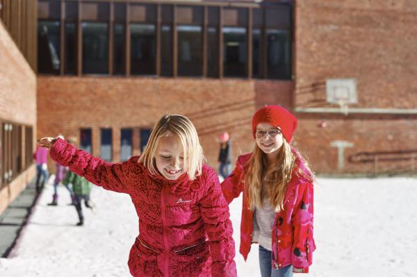 To rødkledde skolejenter leker og koser seg i skolegården. Foto: Øivind Haug