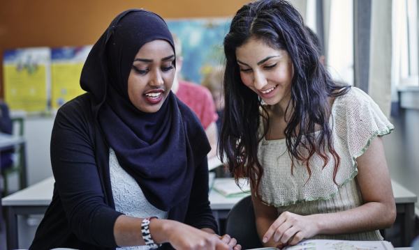 To kvinnelige skoleelver som gjør gruppearbeid i et klasserom.