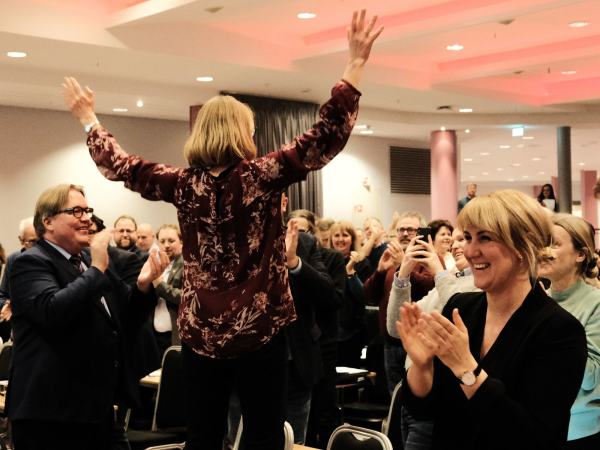 Anniken Huitfeldt står på en stol med armene i været. Årsmøtet klapper, hun er valgt som leder av Akershus Ap.