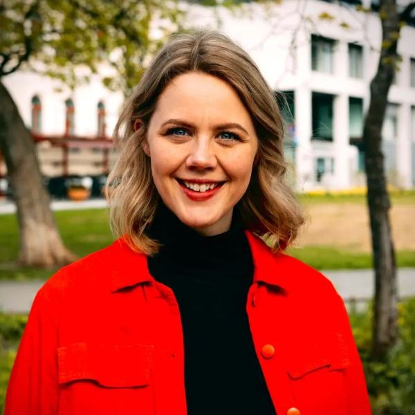 Marta Hofsøy i sort genser og rød jakke på en solværsdag i domkirkeparken i Tromsø.