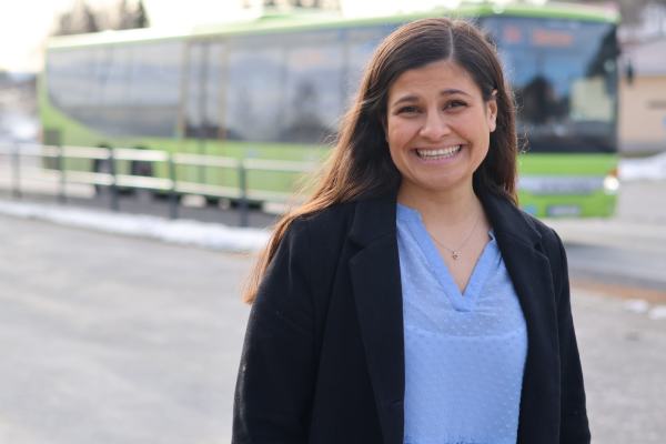Hoda Imad står foran en grønn buss og smiler