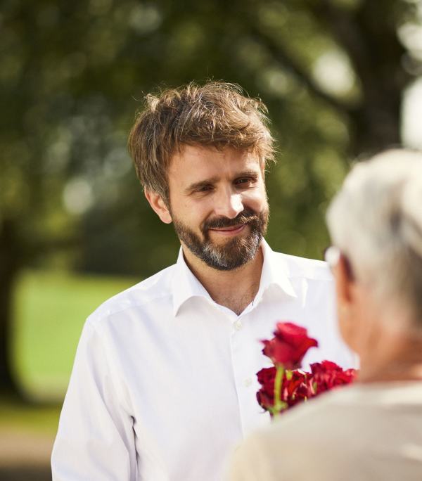 Helseminister Jan Christian Vestre deler ut rose til en eldre dame.