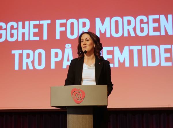 Arbeids- og inkluderingsminister Tonje Brenna står på talerstolen i hvit t-skjorte og svart dressjakke.
