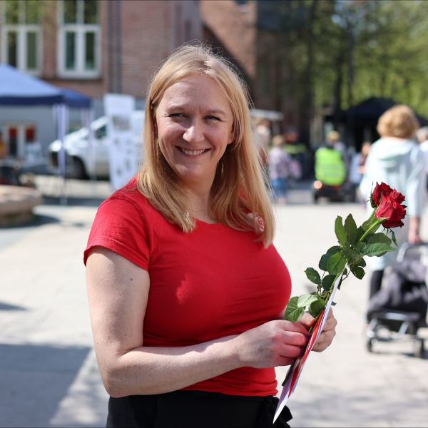 Mette-Gro med rose og flyer i hånden
