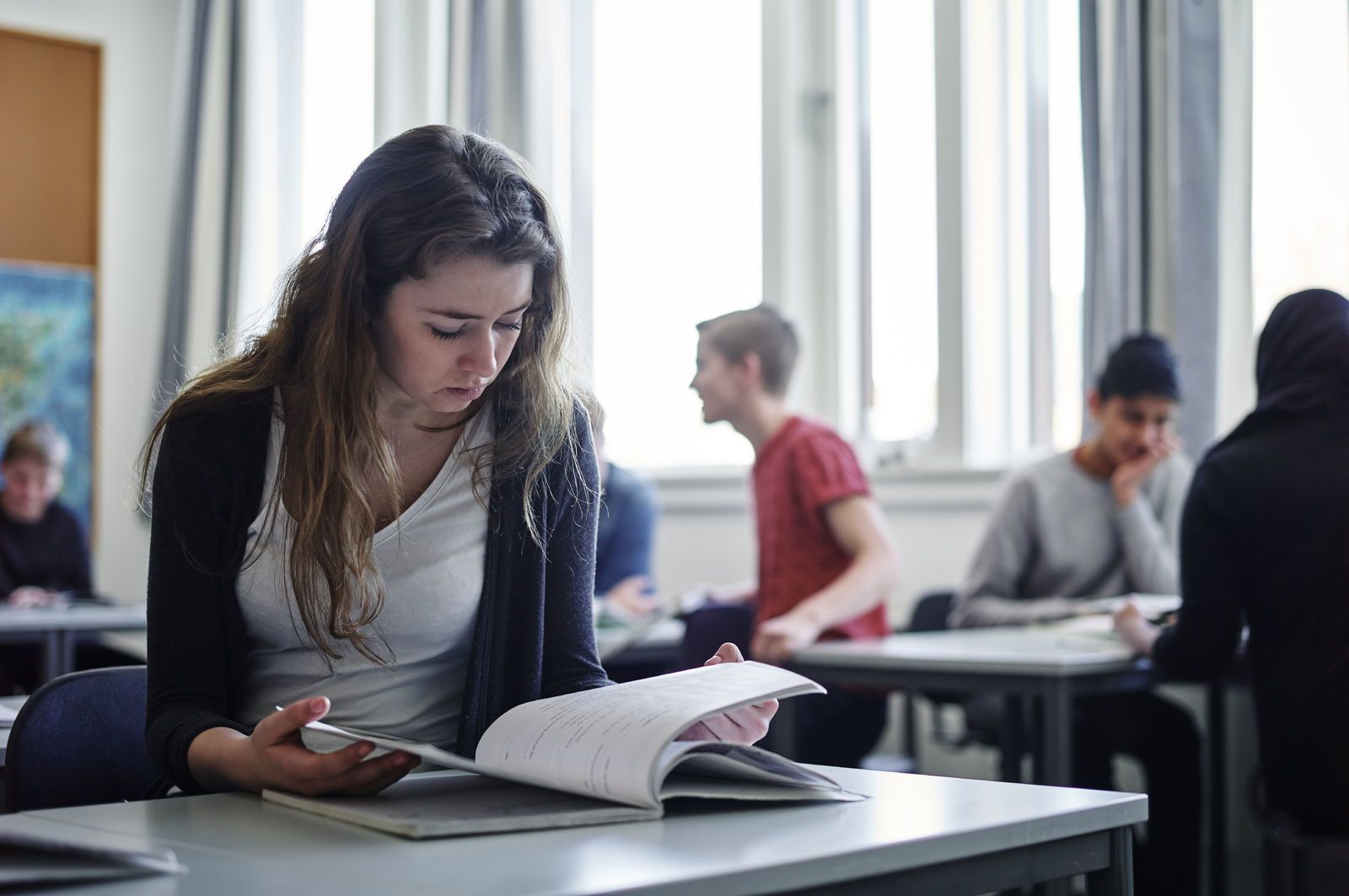 En elev sitter konsentrert ved pulten sin og leser. Foto: Øivind Haug