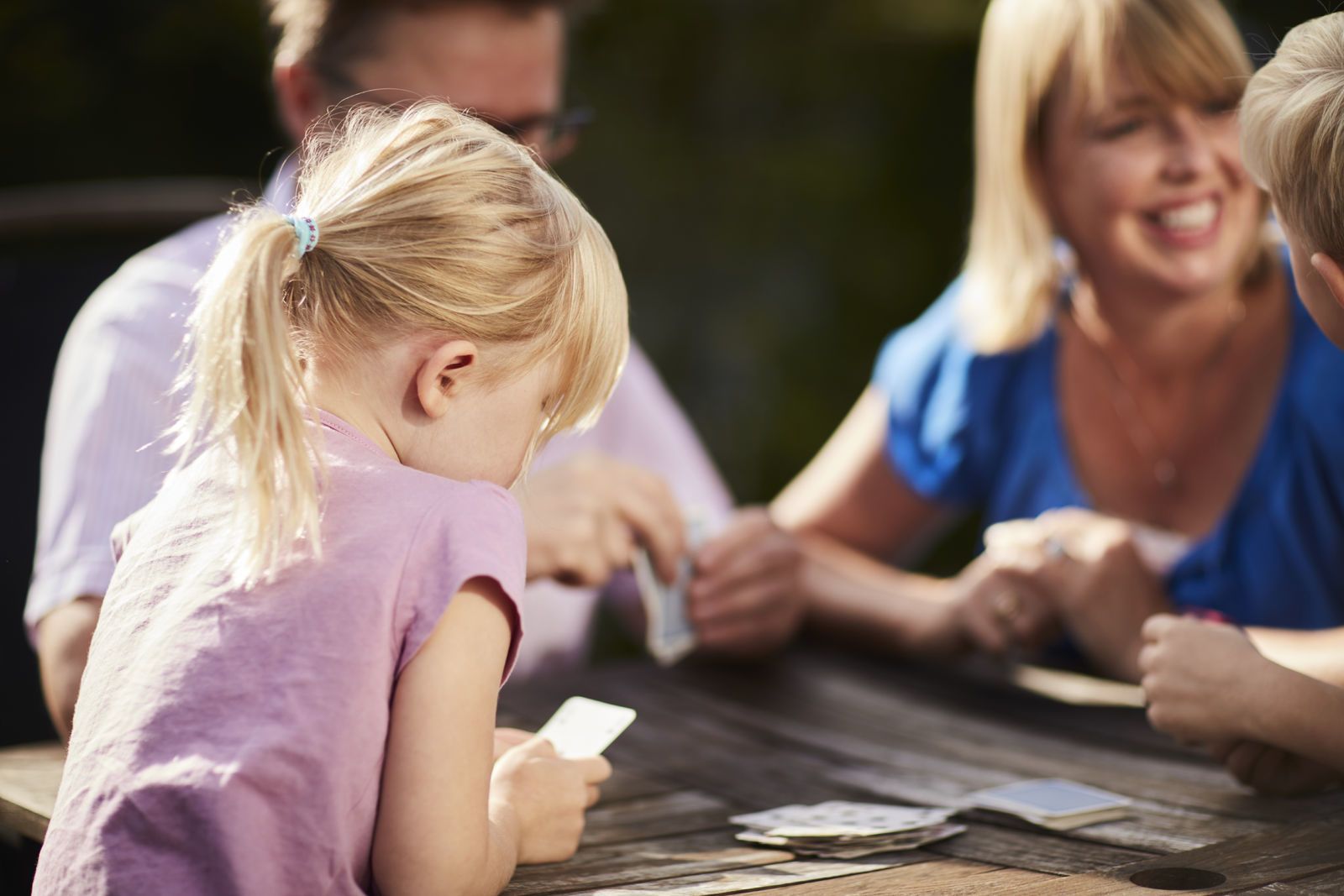 En familie på to barn og to voksne spiller kort utendørs. Foto: Øivind Haug