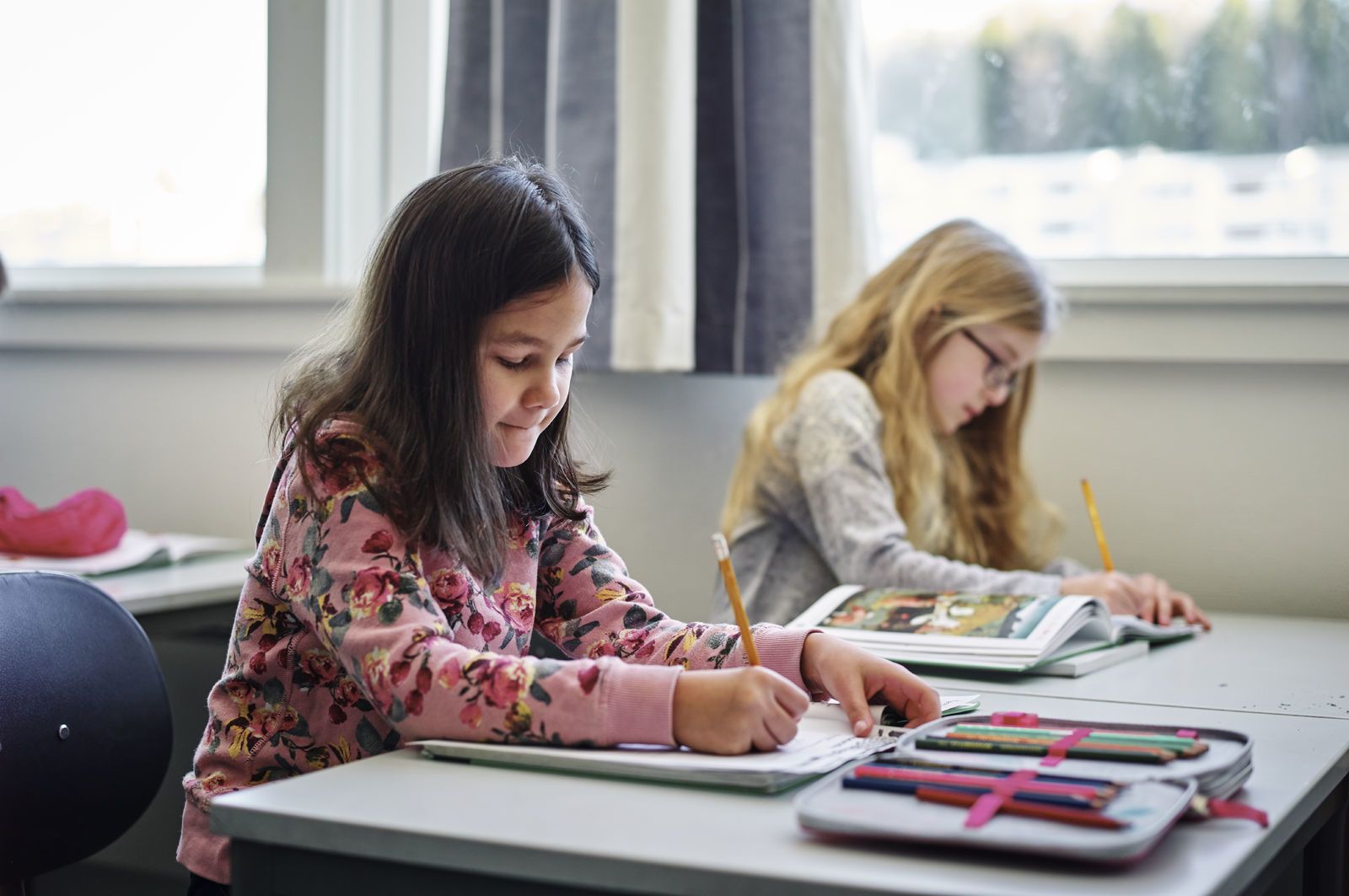 To barneskolejenter sitter og jobber på pultene sine. Foto: Øivind Haug