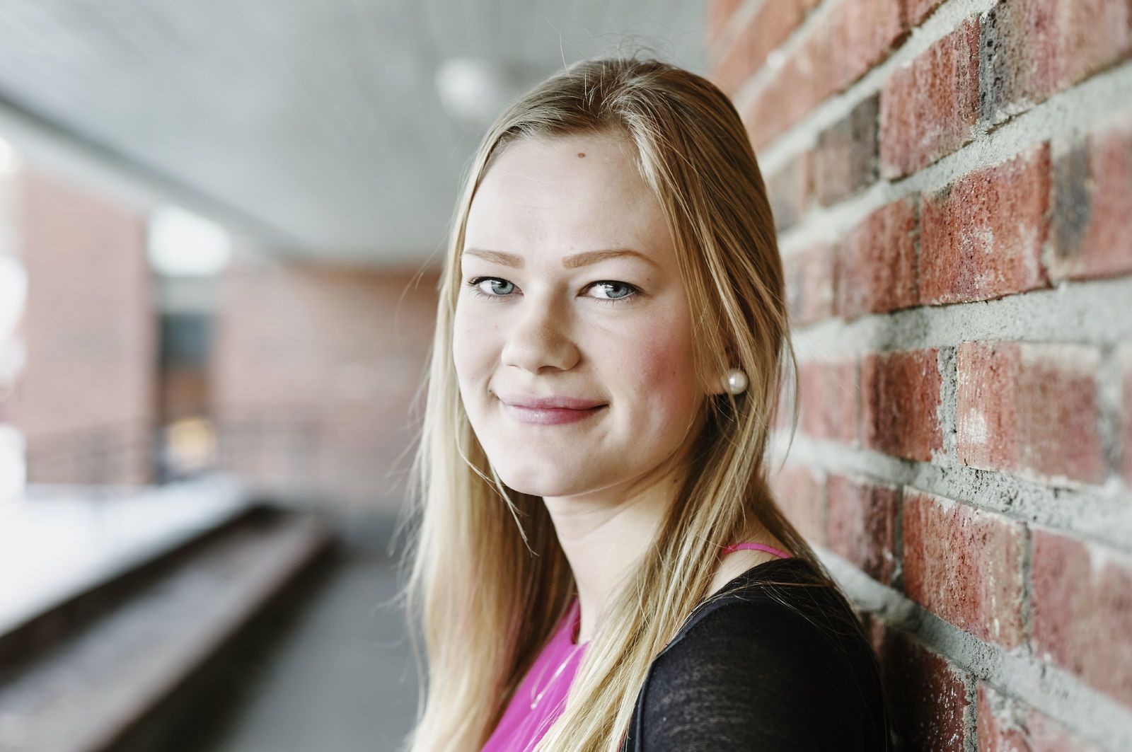 En skoleelev står med ryggen til en murvegg, hodet vendt til siden og ser inn i kamera. Foto: Øivind Haug