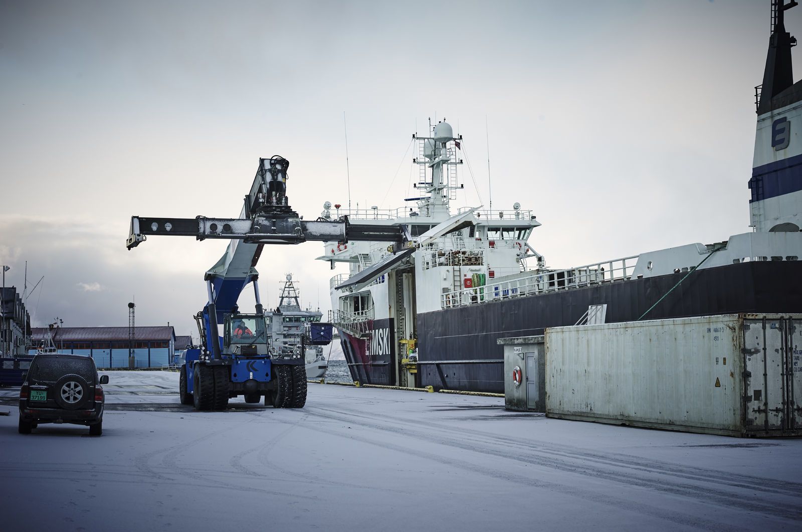 En kranbil kjører forbi et lasteskip som ligger ved havna. Foto: Øivind Haug