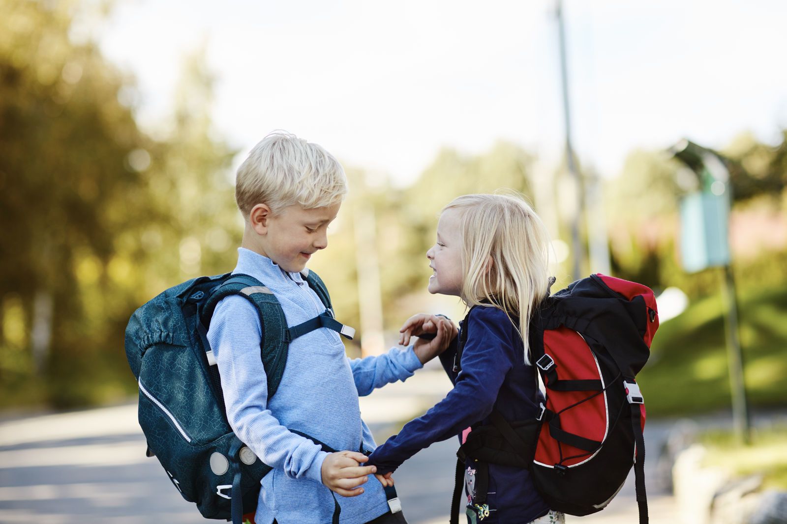 To skolebarn holder hender og smiler på vei til skolen. Foto: Øivind Haug